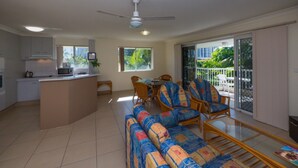 Uma sala de estar ampla com sofá, cadeiras, mesa de jantar e uma cozinha com micro-ondas.