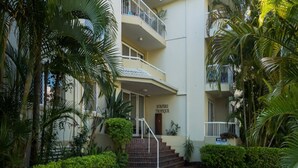 Um edifício de vários andares com uma placa na entrada que diz "SURFERS TROPIQUE".