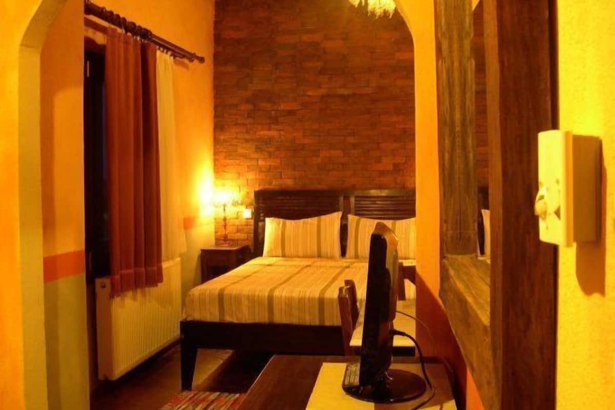 A cozy room with a brick wall, a bed with a wooden headboard, a bedside table, and a lamp.