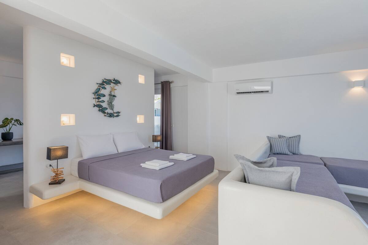 Quarto moderno com uma cama grande, mesas de cabeceira e um espaço de estar.