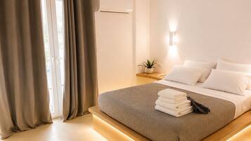 Habitación de hotel con cama, cortinas, mesita de noche con una planta y aire acondicionado de pared.