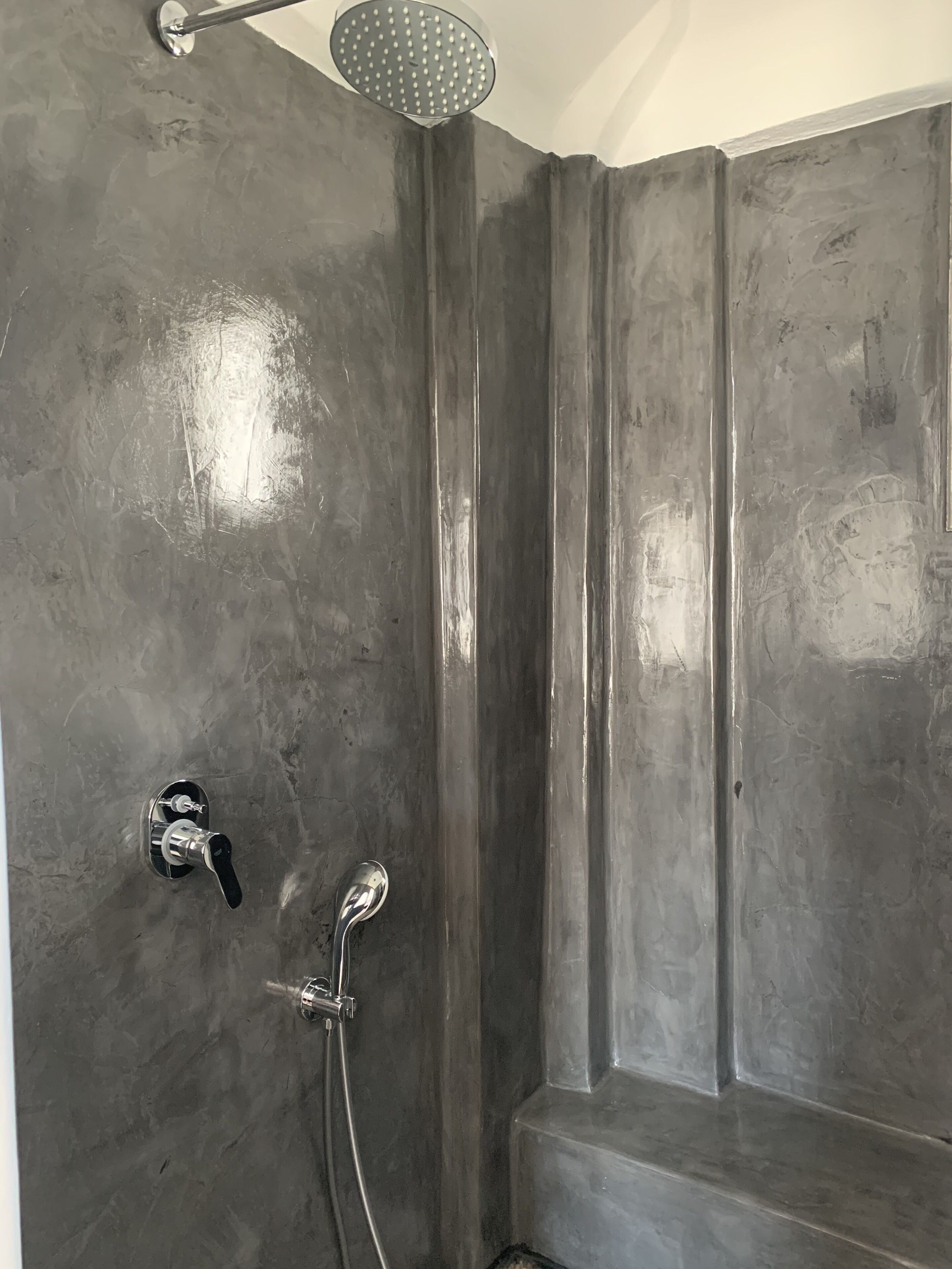 A shower with a handheld showerhead and a wall-mounted faucet.