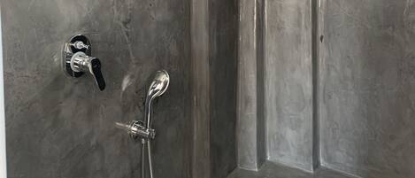 A shower with a handheld showerhead and a wall-mounted faucet.