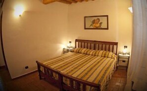 Ein Schlafzimmer mit einem hölzernen Bett, einem Nachttisch, einer Lampe und einem Bild an der Wand.