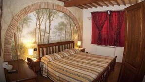 Un dormitorio con cama de madera, mesita de noche, lámpara y un amplio ventanal de arco con un mural de un bosque.