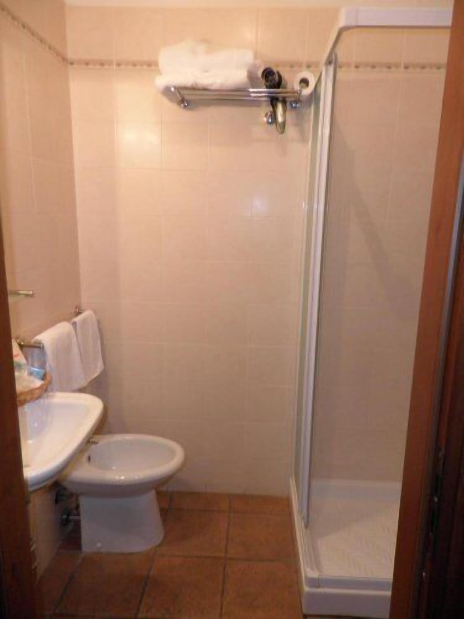 Et badeværelse med toilet, håndvask og brusekabine med glasvægge.