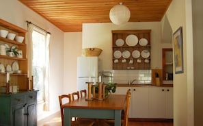 A kitchen with wooden cabinets, a dining table with chairs, and a hanging light fixture.