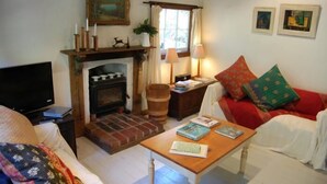 A cozy living room with a fireplace, a television, and a comfortable sofa. - Allenvale (Lorne)