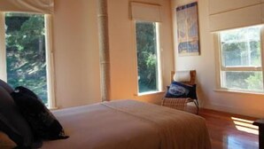 A bedroom with a bed, a chair, a window, and a wooden ceiling. - Allenvale (Lorne)