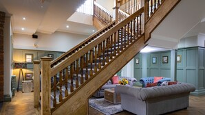 Un salón amplio con una escalera de madera, un sofá gris y piso de madera.
