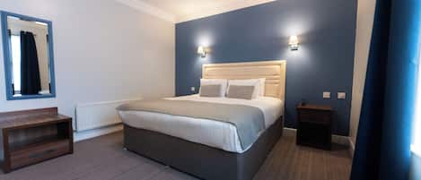 Un dormitorio con cama, mesitas de noche, un espejo y un radiador.