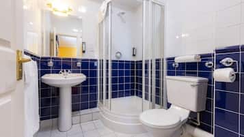 Une salle de bain avec une douche à parois de verre, un lavabo sur colonne et des toilettes.