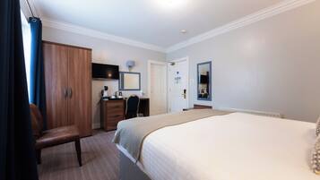Habitación de hotel con cama, escritorio, silla, armario y televisor.