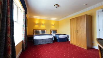 A hotel room with two beds, a wardrobe, and a red carpet.
