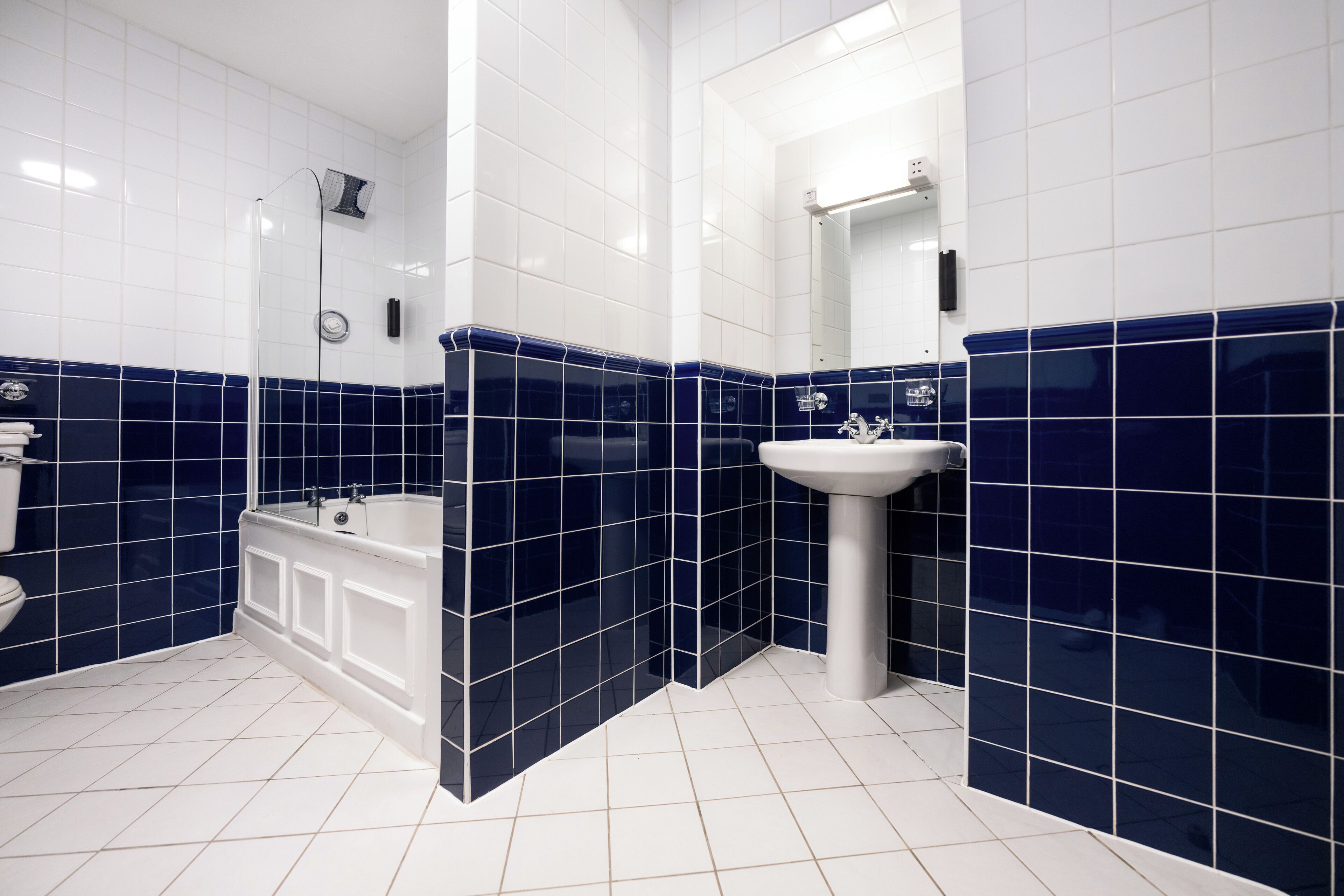 Ein Badezimmer mit weißen und blauen Fliesen, einer Badewanne und einem Waschbecken.