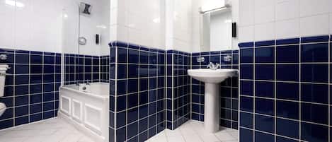 A bathroom with white and blue tiles, a bathtub, and a sink.