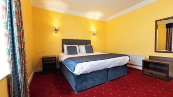 A bedroom with a large bed, yellow walls, and red carpet.