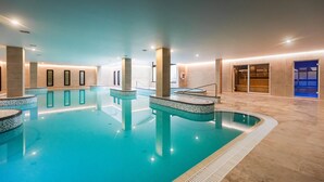 Una piscina interior con agua cristalina, bordes azulejados y un diseño moderno.