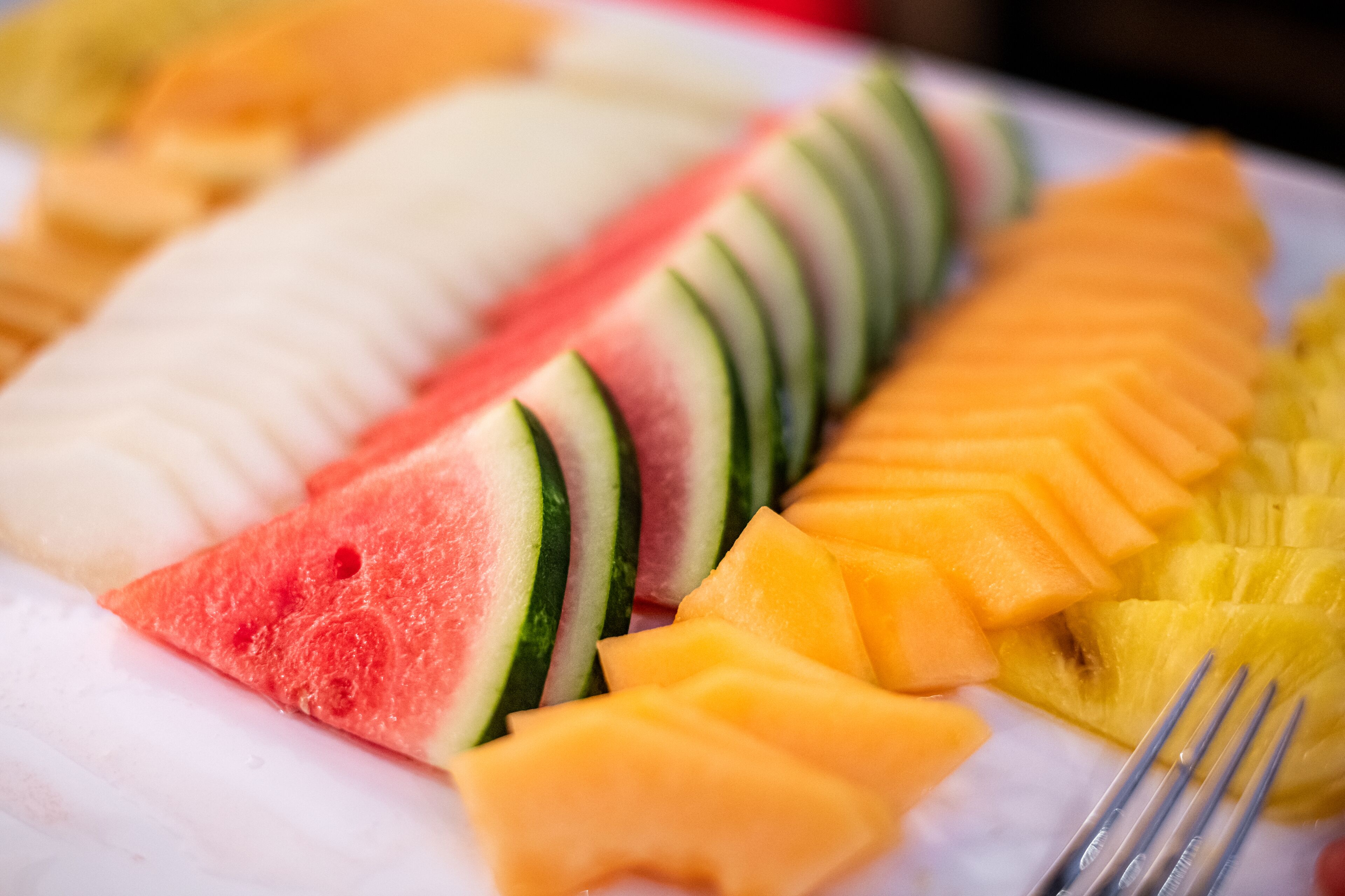 Un plat amb fruita tallada, com síndria, meló i ananas.