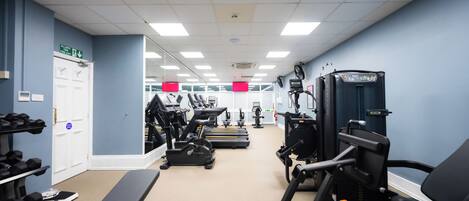 Uma academia com equipamentos de ginástica, esteira e banco de musculação.