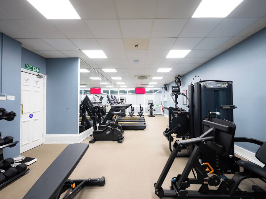 Un gimnasio con equipo de ejercicio, una cinta de correr y un banco para pesas.
