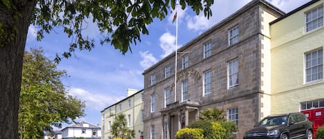 A building with a stone facade, a flagpole, and a parked car in front.