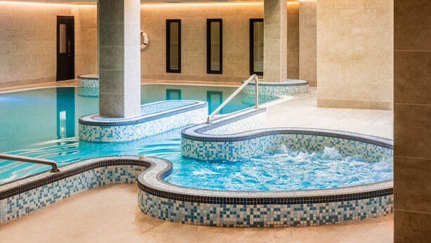 Una amplia piscina interior con varios jacuzzis y una zona de agua cristalina.