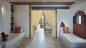 Une chambre avec deux lits, un plafond en bois et une vue sur l’extérieur, visible à travers l’encadrement d’une porte.