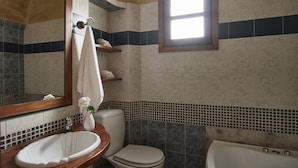 Une salle de bain avec un meuble-lavabo en bois, un lavabo blanc, des toilettes et une baignoire.