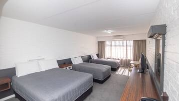 A hotel room with two beds, a desk with a telephone, and a television.