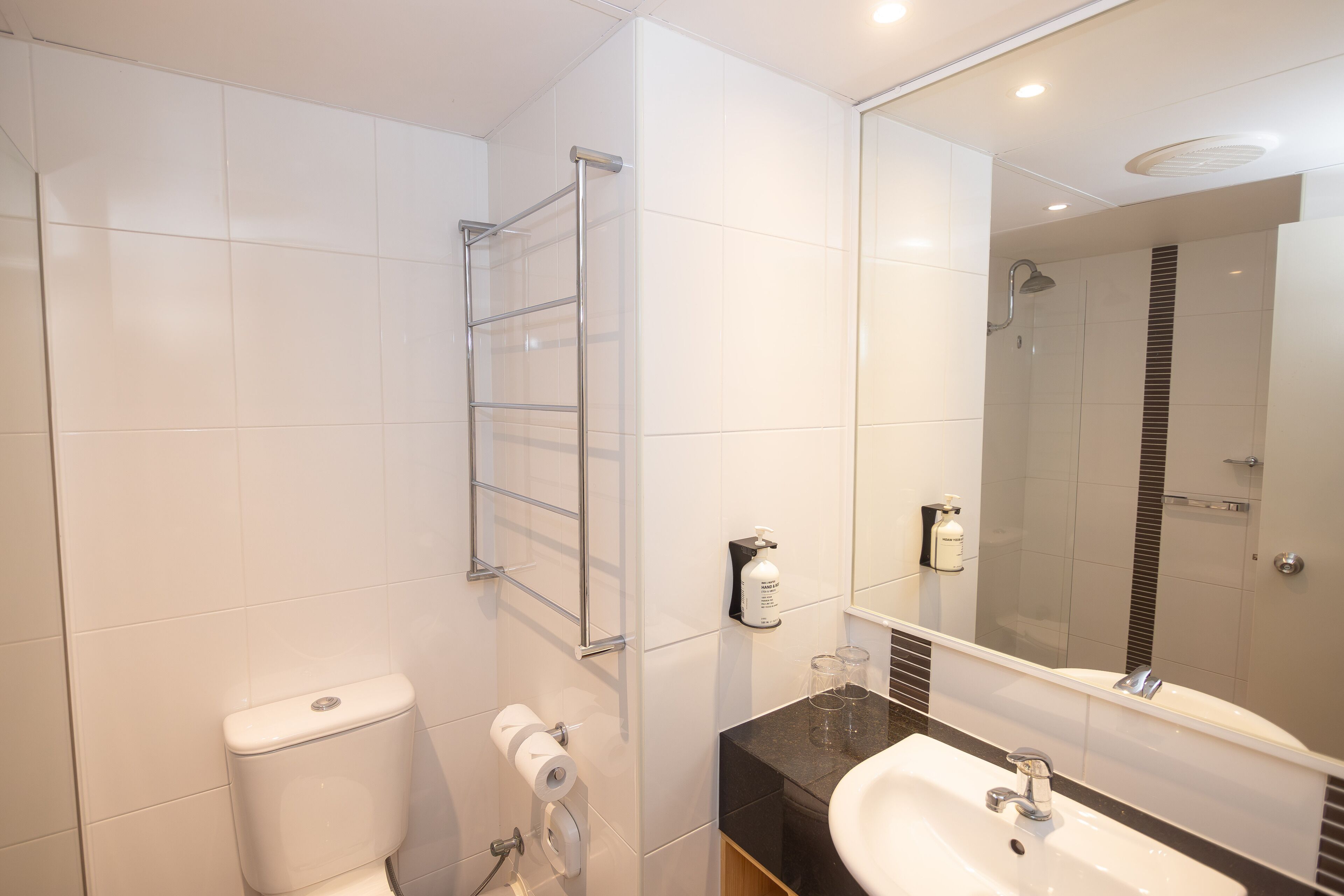 Ein modernes Badezimmer mit Toilette, Waschbecken, einer Duschkabine aus Glas und einem Spiegel.