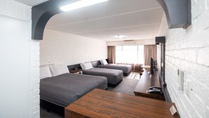 A modern hotel room with two beds, a wooden desk, a flat-screen TV, and a brick wall. - Dog Rock Motel (Mount Clarence)