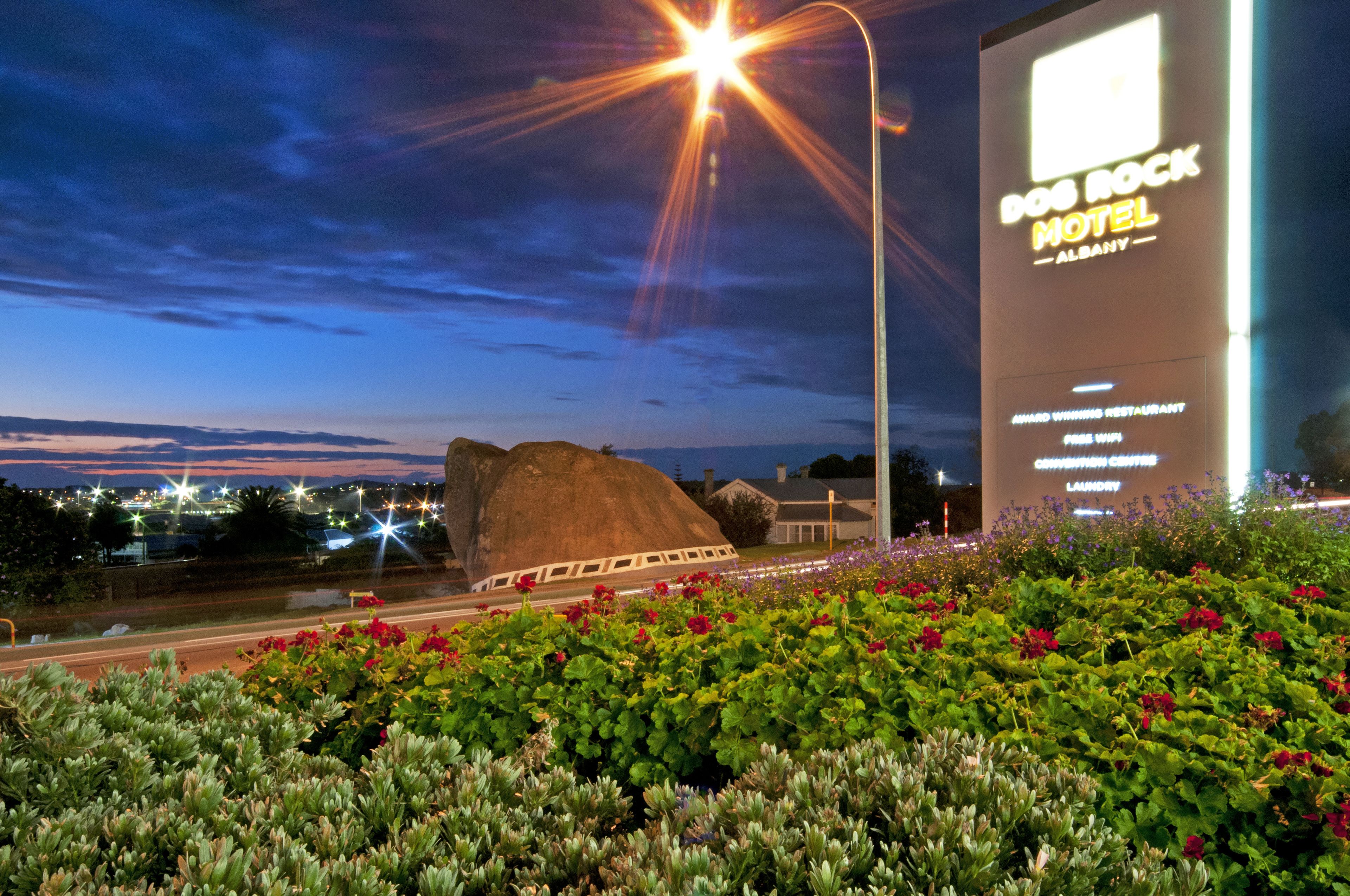 A large rock formation in front of a building with a sign for 'DOD ROCK MOTEL'.