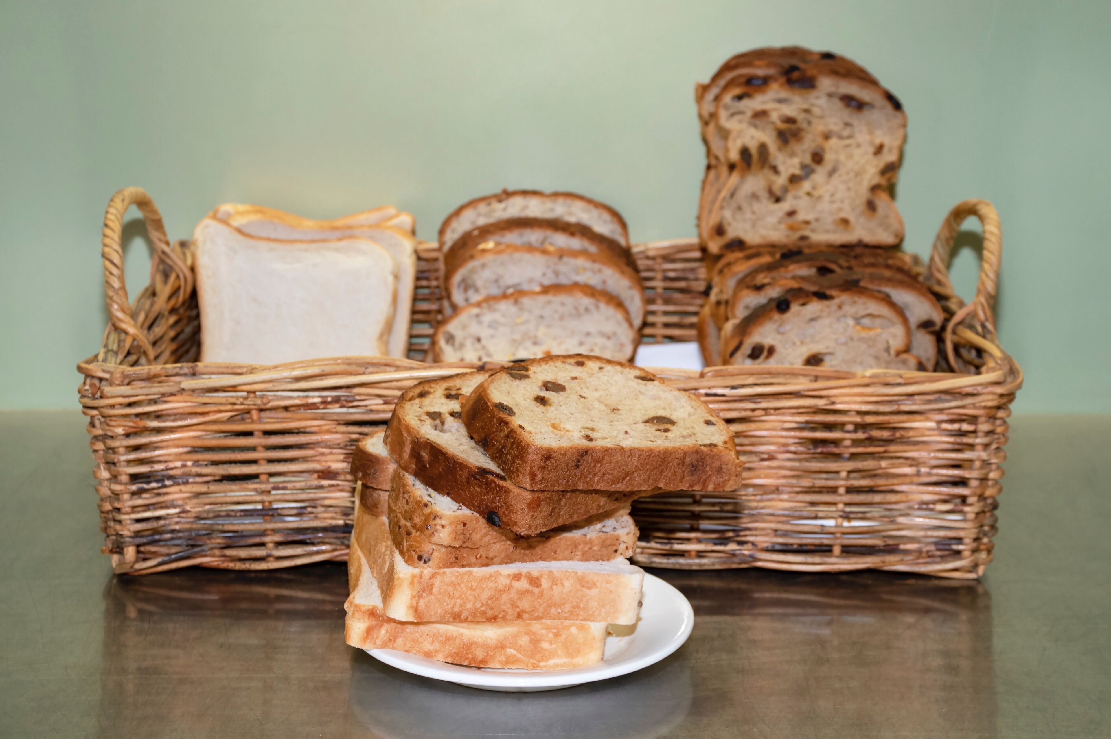 Een rieten mand met verschillende soorten brood, zowel in plakjes als hele broden.
