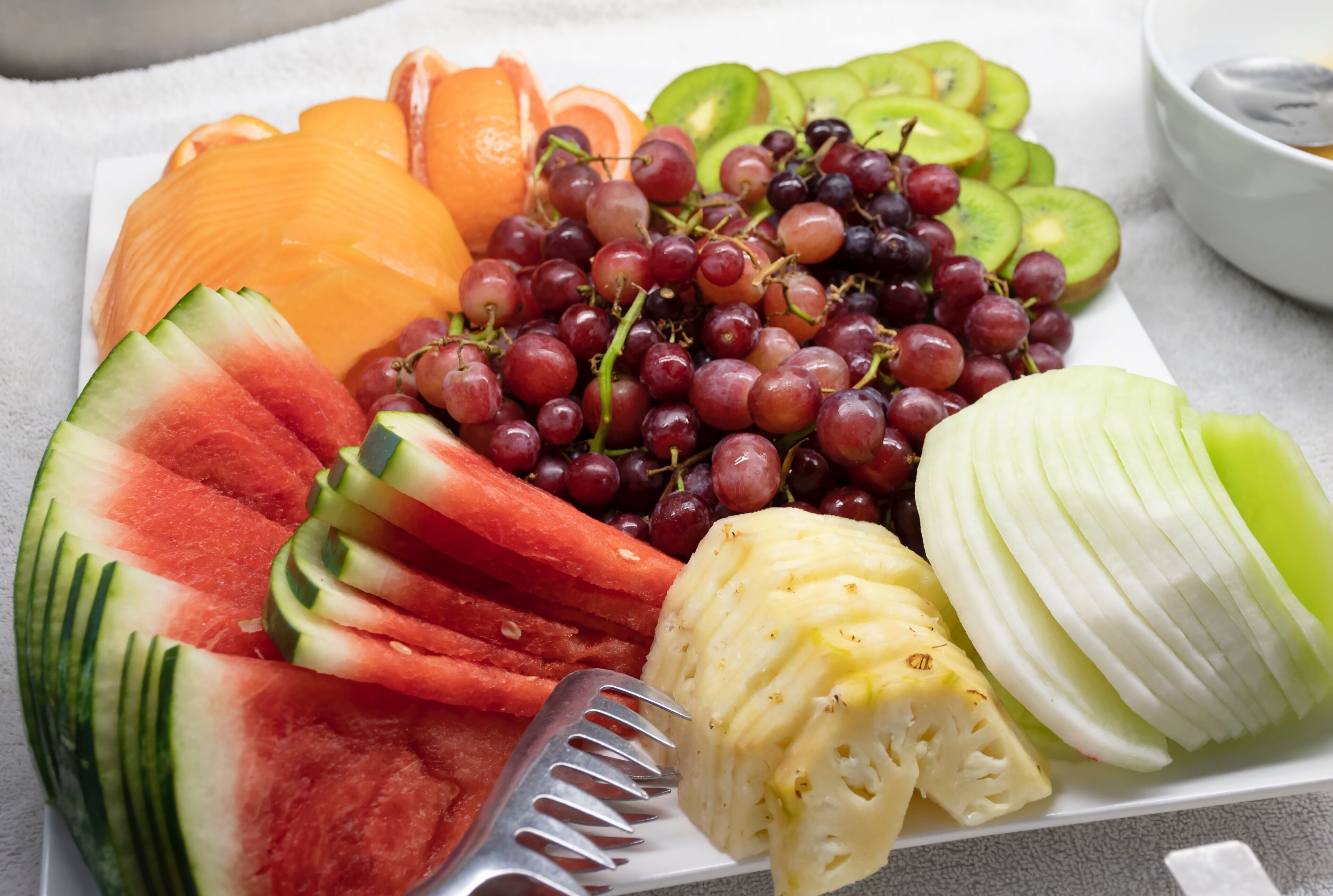 Un plato con una variedad de frutas, como sandía, kiwi, uvas y gajos de naranja.