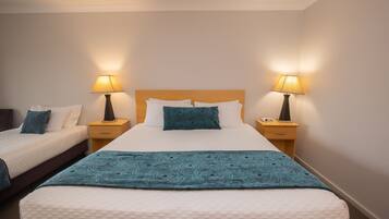 A hotel room with a large bed, two bedside tables, and two lamps.