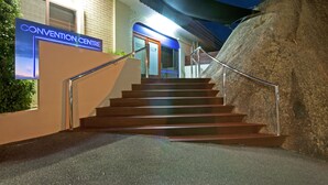 A staircase leading to a building labeled "Convention Centre" with a modern design, including a metal handrail and a large rock on the right. - Dog Rock Motel (Mount Clarence)
