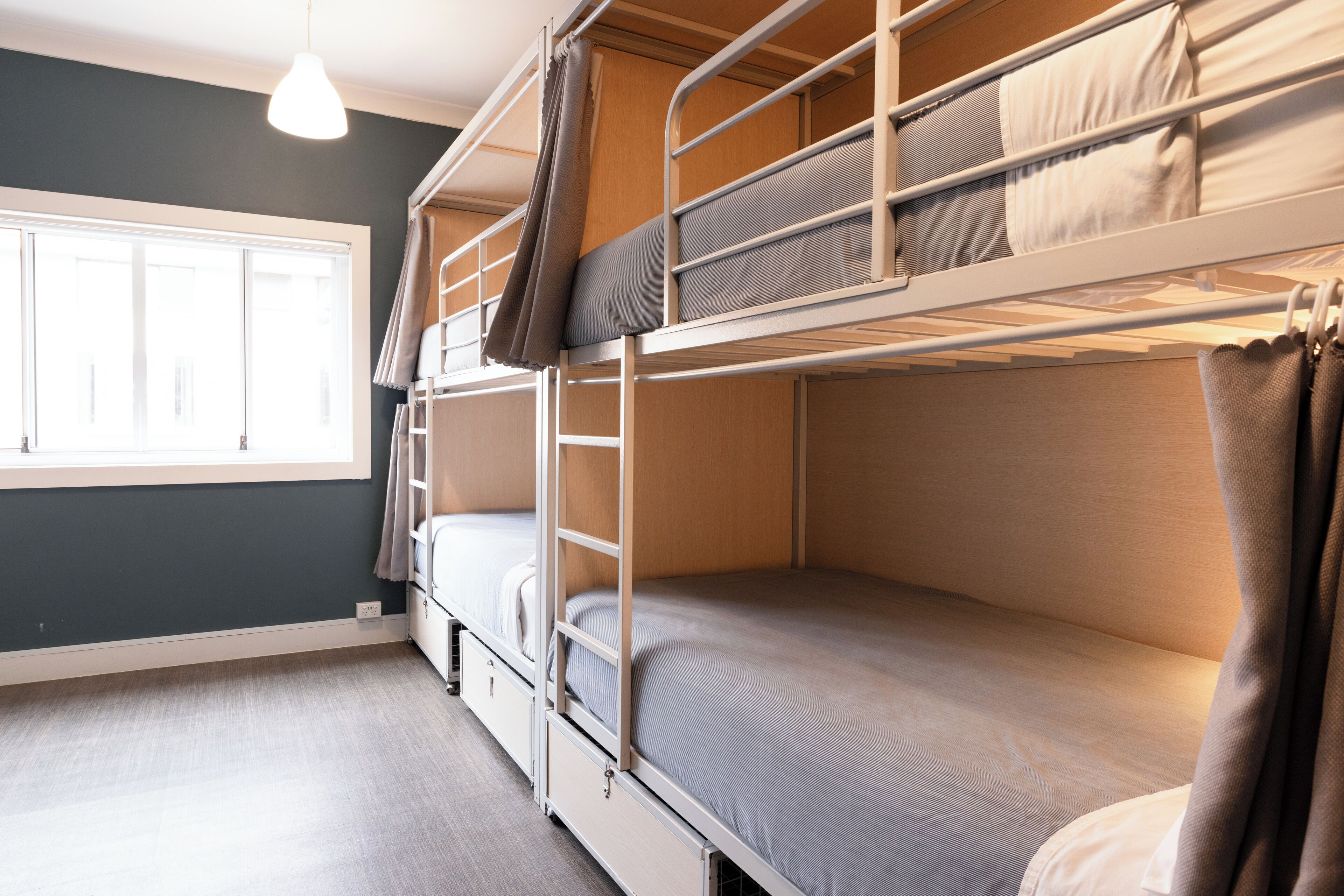 Quarto com beliche, escrivaninha e luminária suspensa.