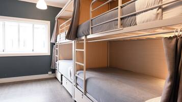 Une chambre avec un lit superposé, une fenêtre, un bureau et un luminaire suspendu.