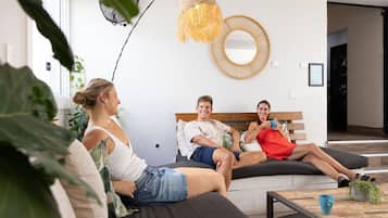 A modern living room with a curved sofa, a round mirror, and a hanging light fixture.