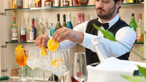 A bartender preparing drinks with a variety of bottles in the background. - Albergo Battelli - Adults Only  (Pietrasanta)