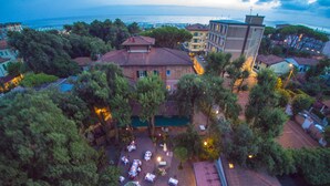An aerial view of a courtyard with outdoor seating, surrounded by trees and buildings. - Albergo Battelli - Adults Only  (Pietrasanta)