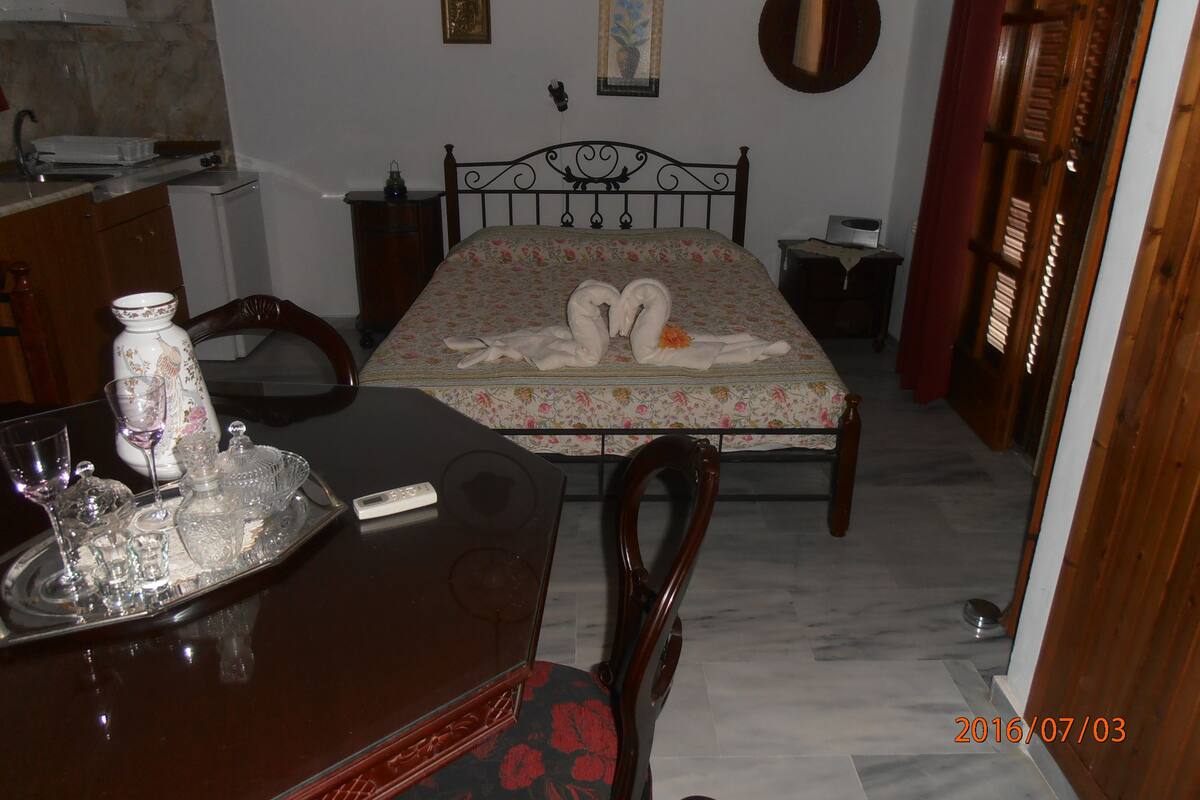A bedroom with a bed, a bedside table, a dresser, and a dining table with chairs.