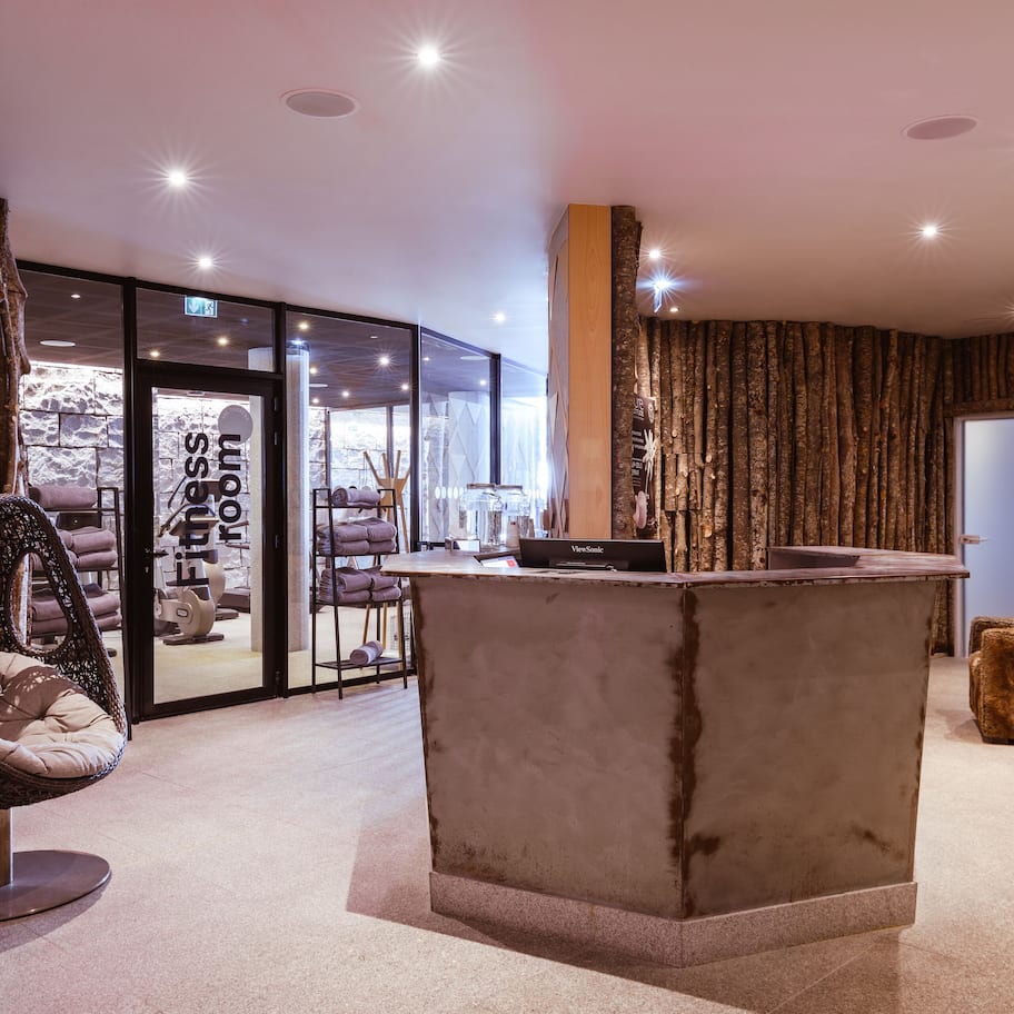 A modern interior with a reception desk, a hanging chair, and a view of a spa area.