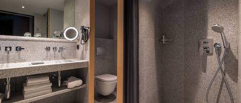 A modern bathroom with a granite countertop, a toilet, and a shower area.