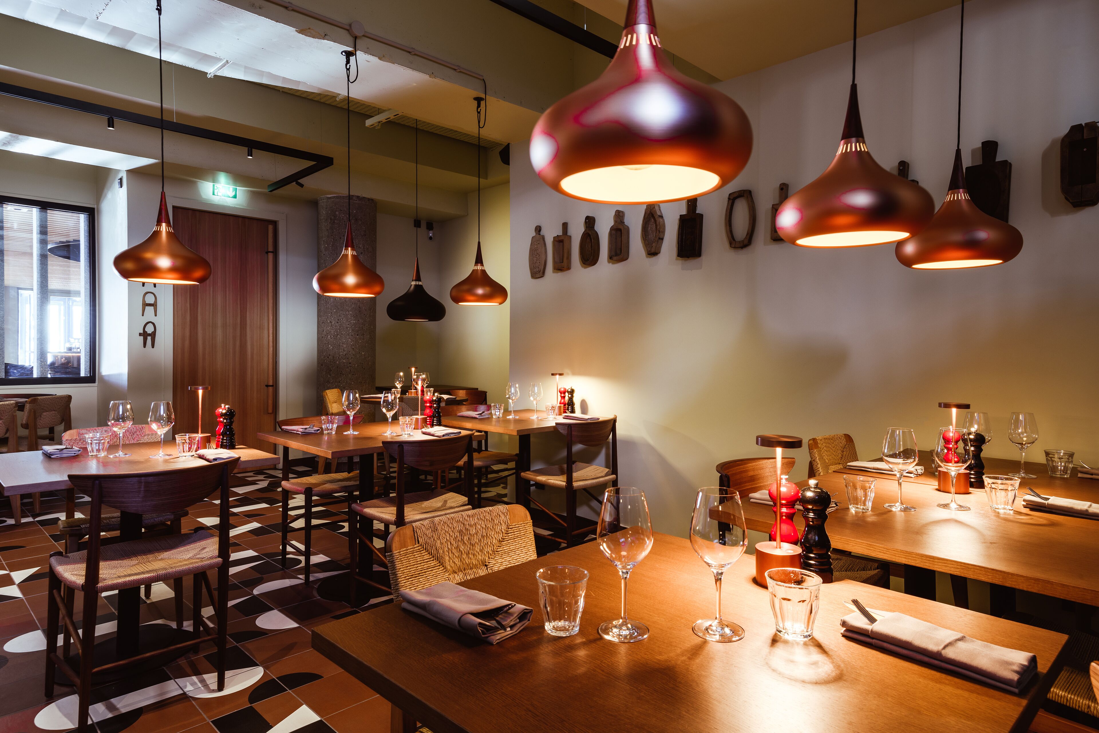 A restaurant with multiple tables set for dining, each with wine glasses and cutlery.