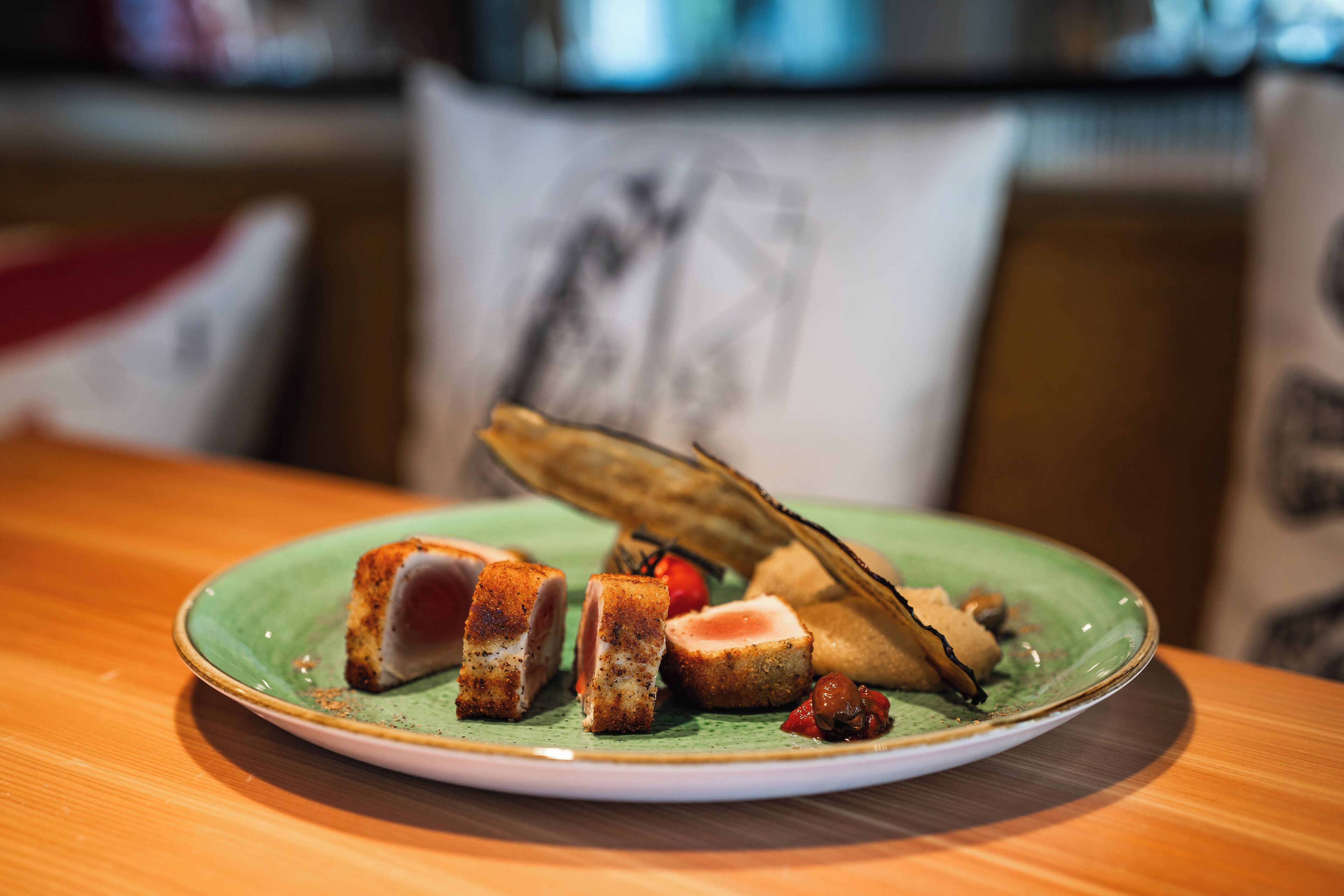 Une assiette remplie de différents aliments, notamment un morceau de viande et un légume, le tout présenté sur une assiette verte.