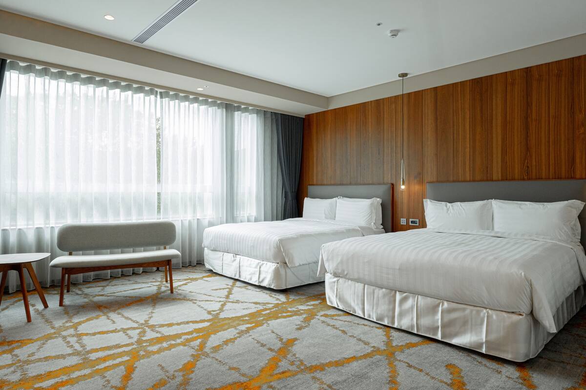 Une chambre d’hôtel avec deux lits, un banc et une petite table.