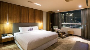 A modern hotel room with a large bed, a nightstand, a chair, and a view of the city at night. - Home Hotel (Taipei)