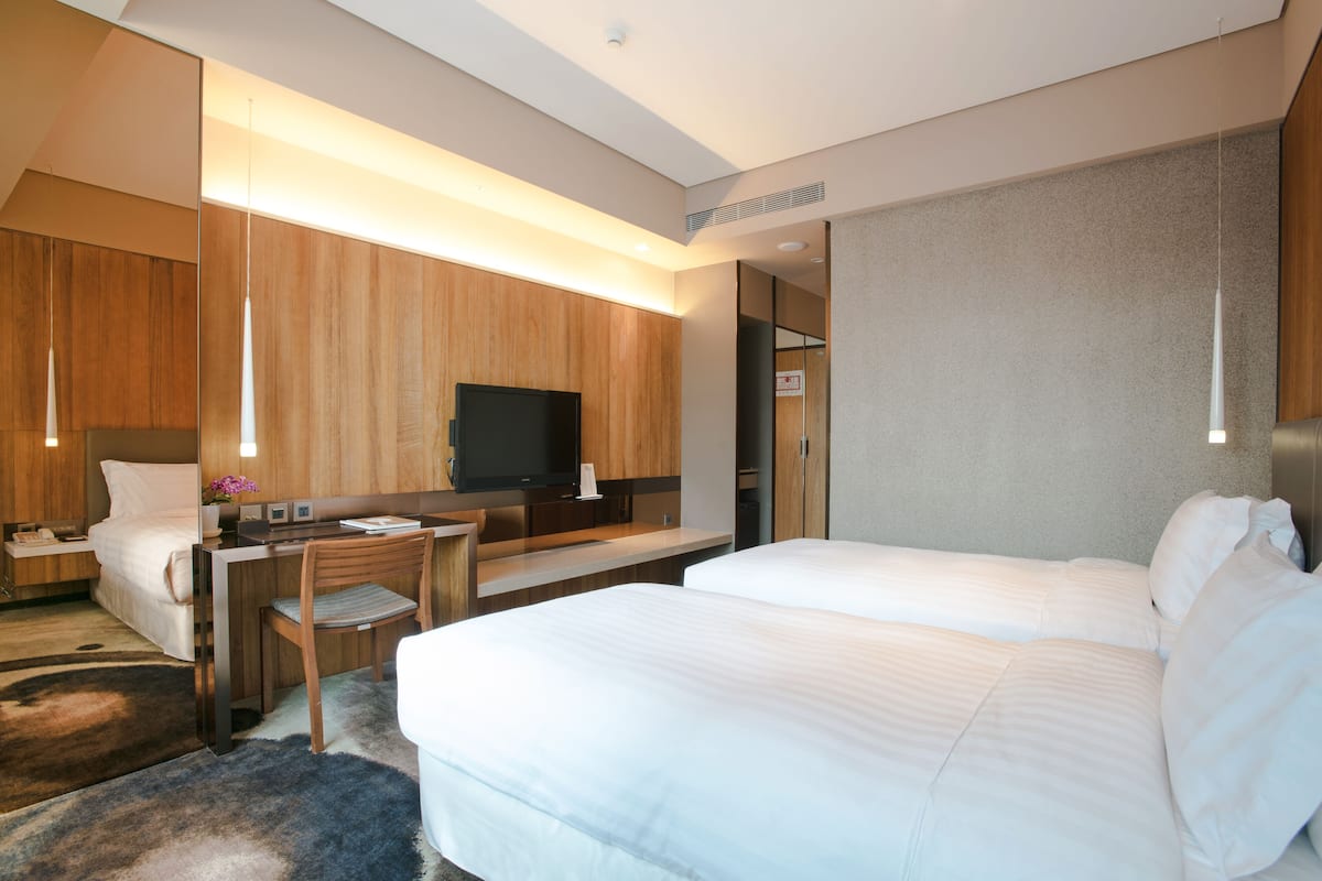 Une chambre d’hôtel avec deux lits, un bureau, une télévision et un miroir.